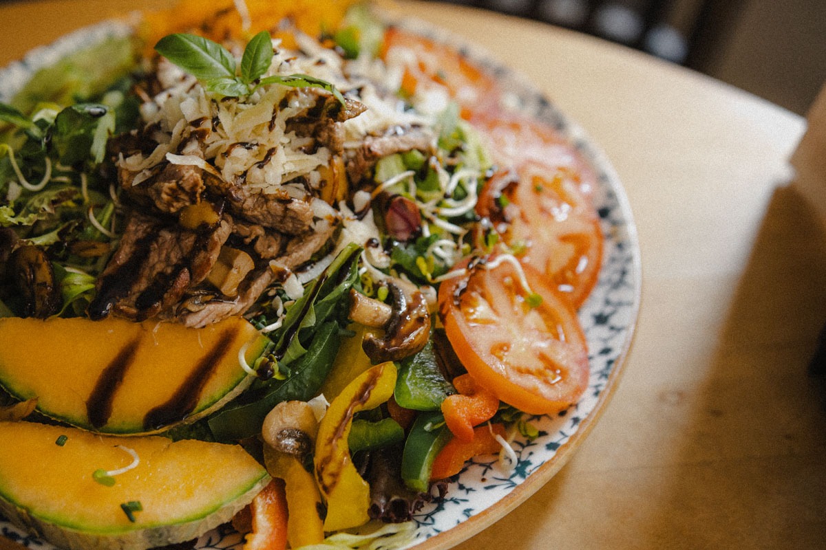 Ein firscher Sommer-Salat mit garniert mit Rinderstreifen, Melonen, Tomaten und Parmesan
